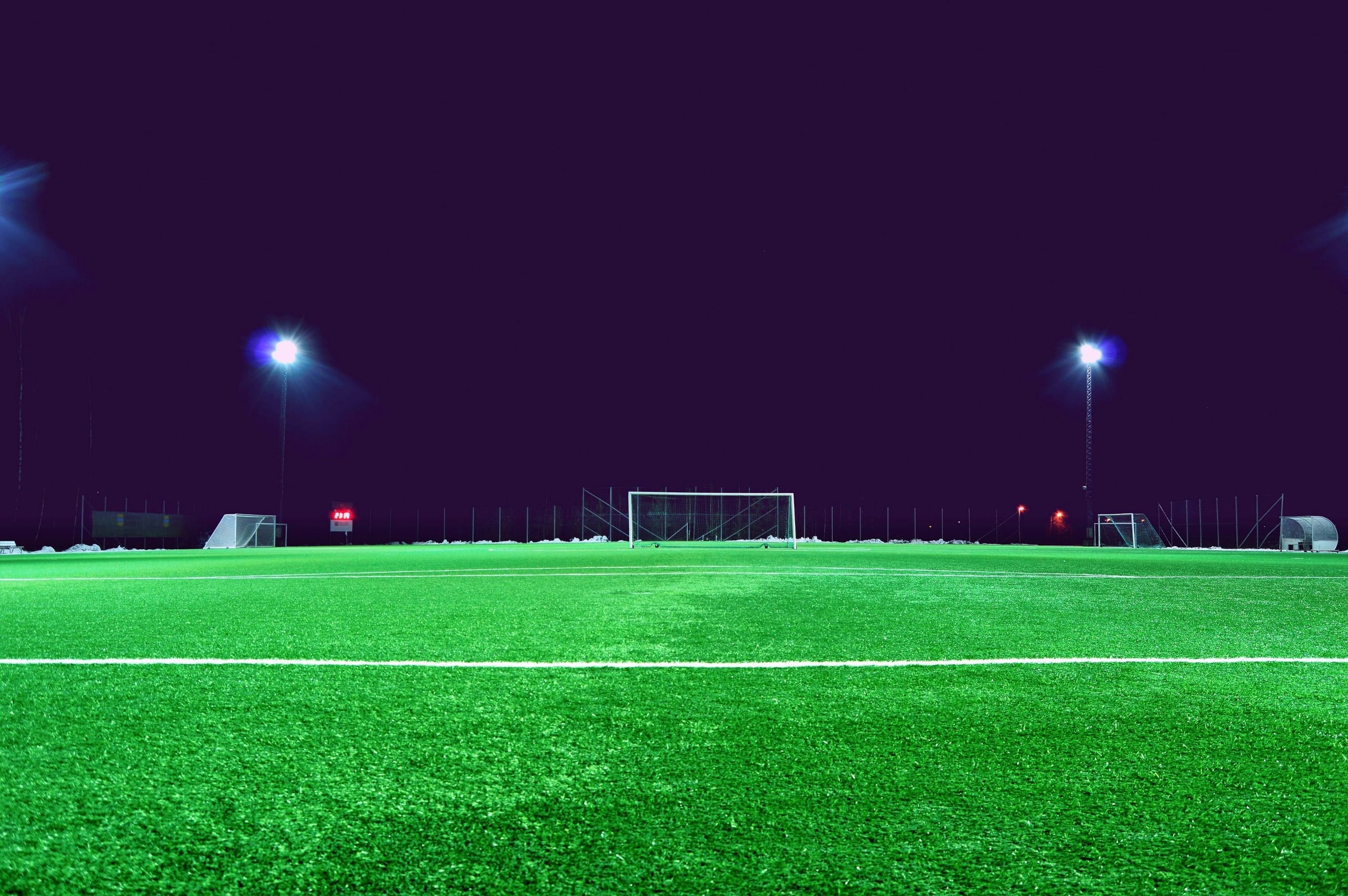 A green soccer field illuminated by bright stadium lights at night